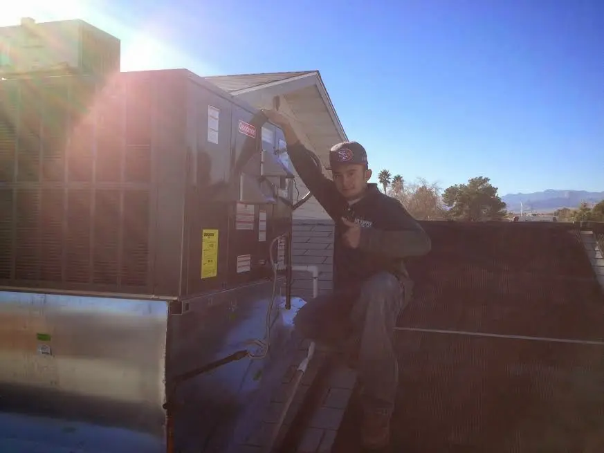HVAC technician performing Heat Pump Repair on a rooftop unit in Hollis